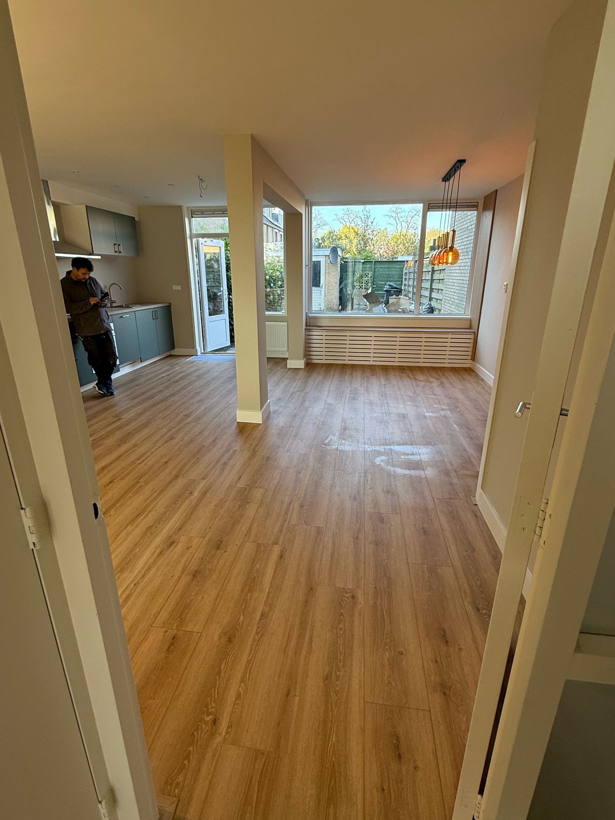 Woonruimte met nieuwe vloer, lichte wanden en keukenhoek