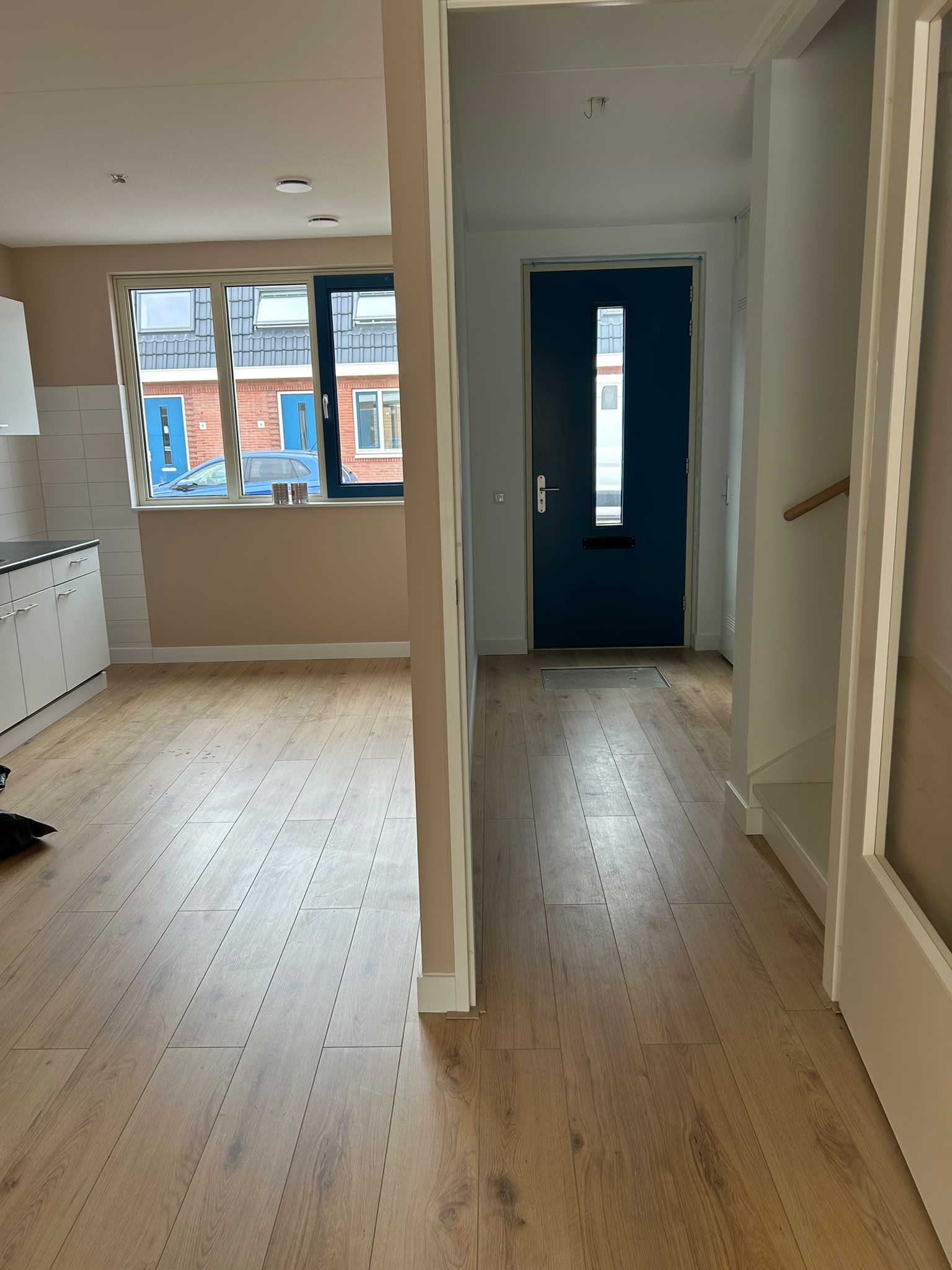 Entree en keuken met beige wandafwerking en zwarte deur