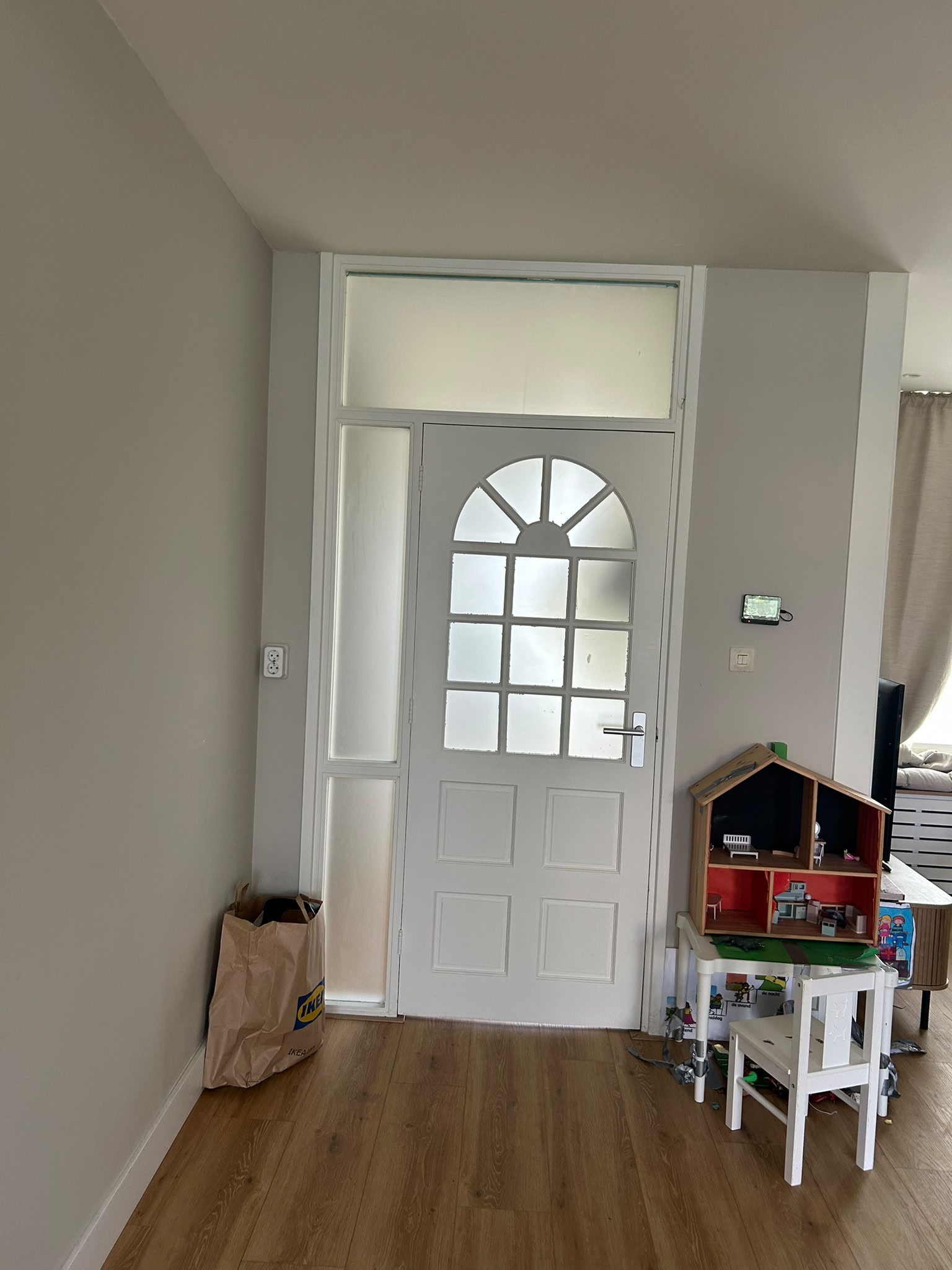Entreehal met witte voordeur en lichte vloer